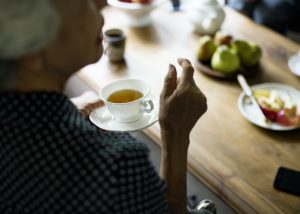 Rear view of senior asian woman holding tea cup talking with friends