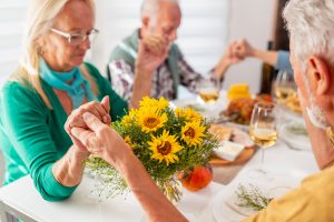 Elderly people praying before Thanksgiving dinner