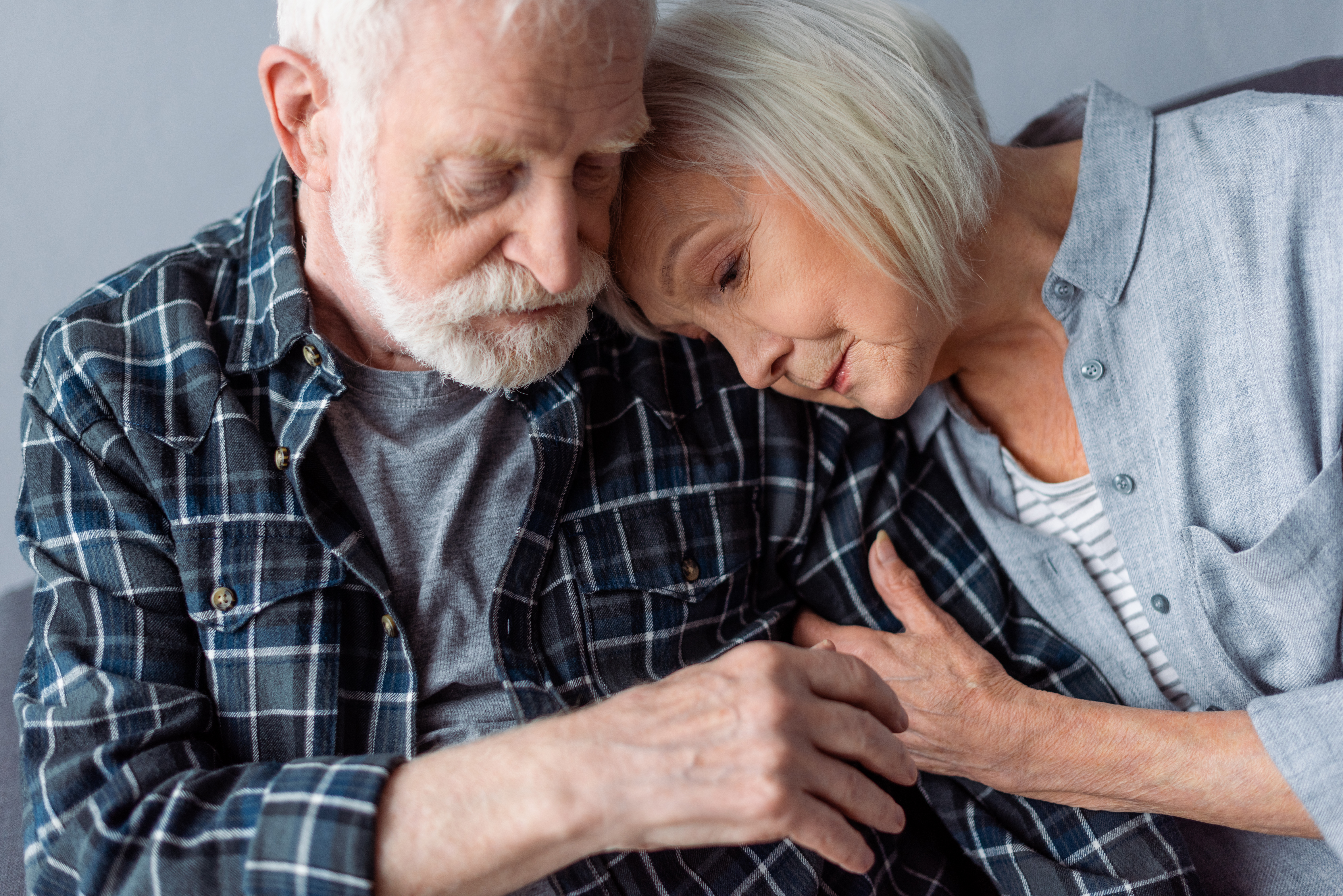senior woman hugging and leaning on old man with dementia disease